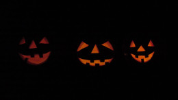 Three carved jack o lanterns in the dark on a spooky October night.