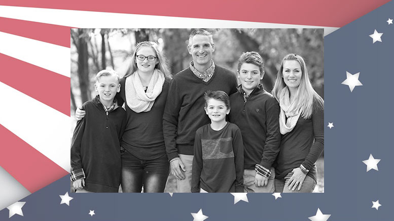 A photo of a family in front of an american flag.