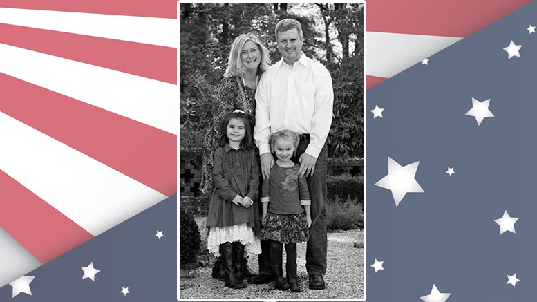 A photo of a family in front of an american flag.