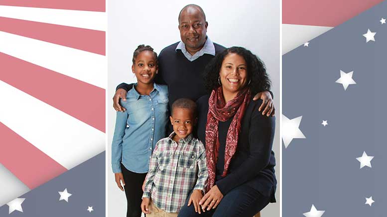 A family is posing in front of an american flag.