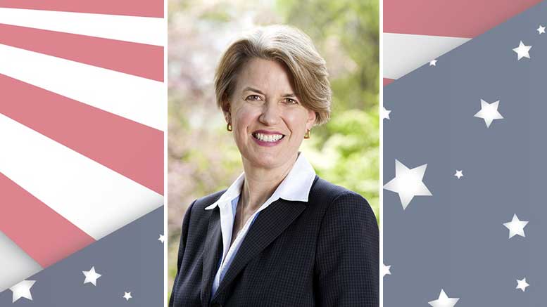 A woman is standing in front of an american flag.