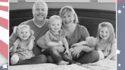 A family is posing in front of an american flag.