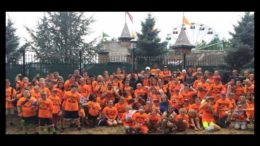 A group of children in orange shirts posing for a photo.