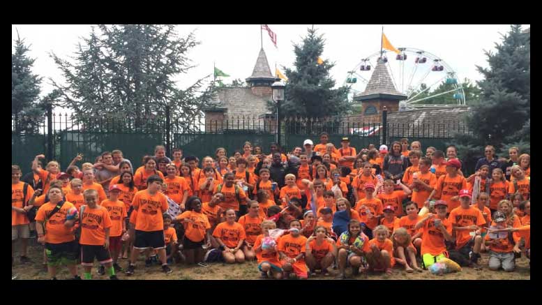 A group of children in orange shirts posing for a photo.