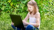 Girl with laptop doing summer homework and reading es tutoring