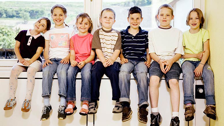 A group of children sitting on a window sill.