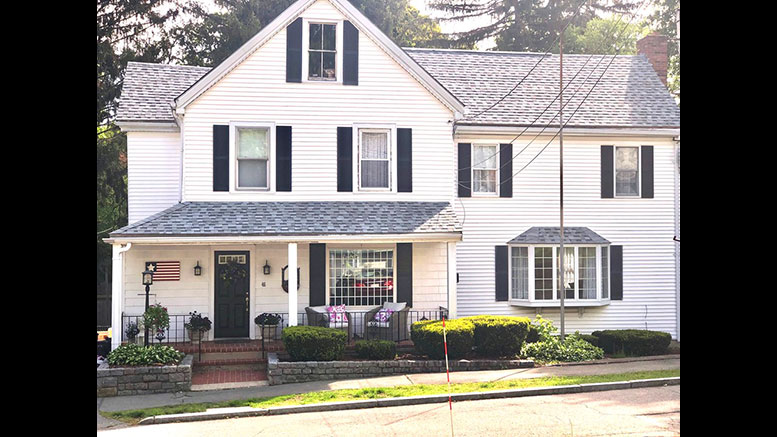 A white house with black shutters and a front porch.