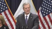 A man and woman standing at a podium in front of american flags announce the Governor's declaration of emergency to temporarily prohibit the sale of vaping products.