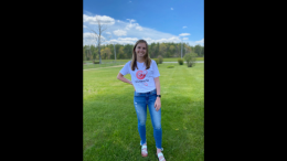 A girl in jeans and a t-shirt standing in a field while launching a free resource hub for aspiring young entrepreneurs.