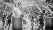 A black and white photo of children playing in a fountain captured by the photographer Lauren Lombard.