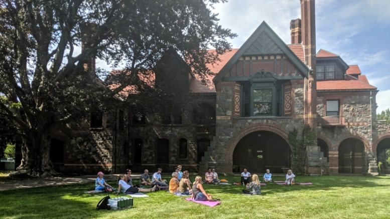 A group of people practicing mindfulness in front of an old house during a walking meditation session at the Eustis Estate on October 17.