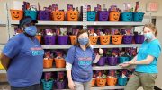 Three people in masks distributed 450 'Boo Buckets' to local children on the South Shore, standing in front of a shelf full of pumpkins.