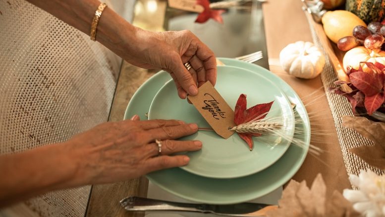 A woman from the Milton Interfaith Clergy Association is placing a place setting on a table, as they prepare for the annual Thanks for Giving Service.