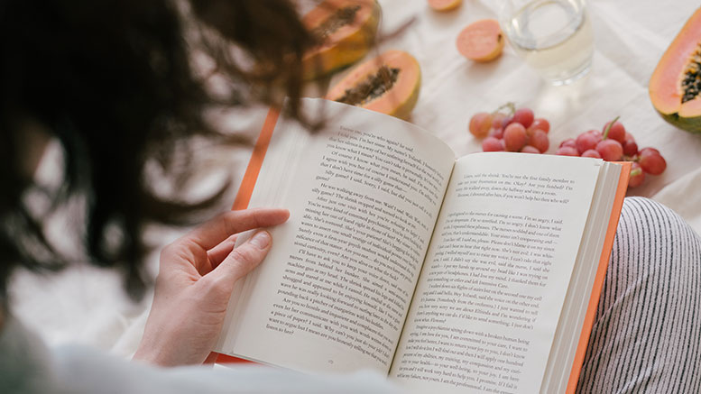 woman reading book in bed