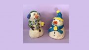 Two snowmen figurines on a purple background, perfect for Winter 2021.