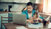 man working on computer with child on lap