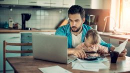 man working on computer with child on lap