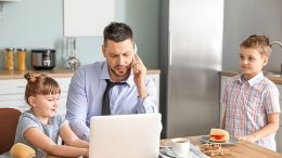 Dad on phone and laptop with kids