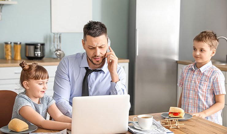 Dad on phone and laptop with kids