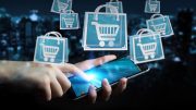 A hand holding a smartphone with shopping carts flying out of it, highlighting the perfect opportunity to invest in your own ecommerce business!
