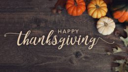 Happy Thanksgiving with pumpkins on a wooden background.