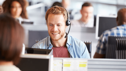 A man wearing a headset in a customer service call center, one of the hardest-hit departments in a small business.