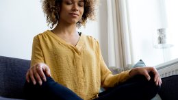 A woman practicing mindfulness on a couch.