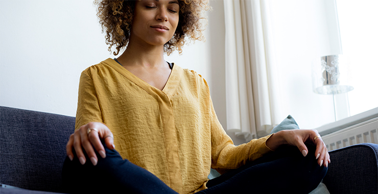 A woman practicing mindfulness on a couch.