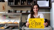 A confident woman holding an open sign confidently moves forward with her plans.