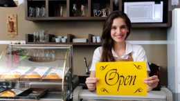 A confident woman holding an open sign confidently moves forward with her plans.