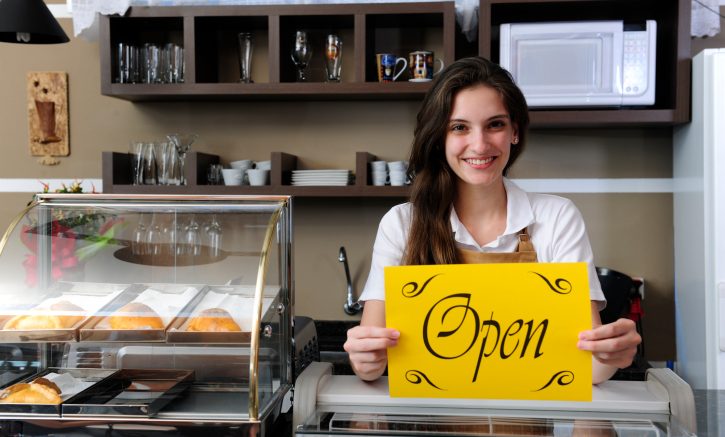 A confident woman holding an open sign confidently moves forward with her plans.