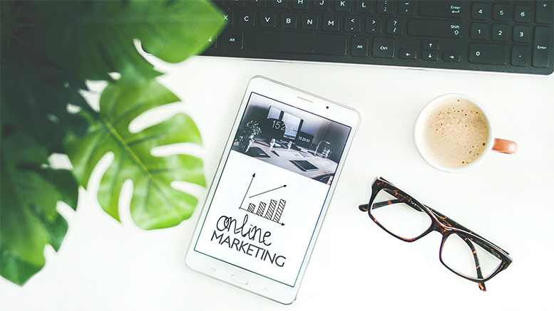 desk with computer keyboard, tablet, glasses, and coffee - with online business marketing strategy graphic on phone