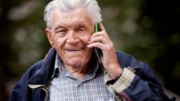 An elderly man participating in the 'Are You OK?' program in Norfolk County, talking on a cell phone for regular well-being checks.