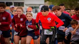 A man in a red shirt is running in the Interfaith’s Stop the Stigma 5K race.