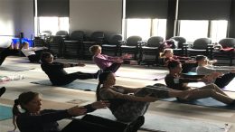 Milton Public Library announces adult programming for April 2024: group of people practicing yoga in a studio setting.