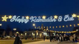 Celebratory lights spelling "happy Ramadan & eid" above a crowd gathered at dusk, embodying devotion and community during Ramadan 2024: A time for reflection.