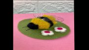 A crafted felt bee on a green oval mat with two white and pink flowers, set against a pink background with a white tiled pattern, invites you to discover Chair Yoga with Marianne Zullas on