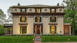 An elegant, historic two-story building at dusk with lighting accentuating its architectural features.