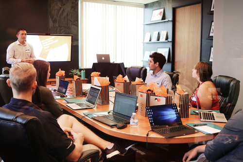 A corporate training session focused on the 2024 European job market in a modern conference room with a presenter and several attendees, including Americans, seated around laptops.