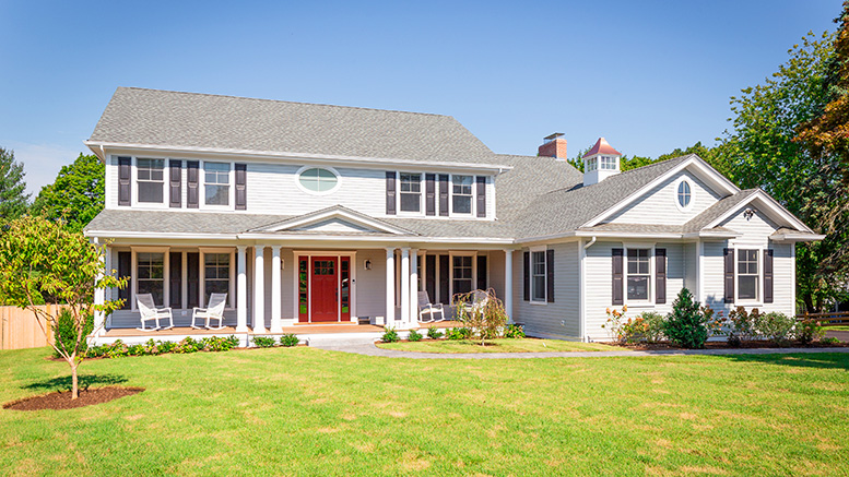 Discover excellence in architecture with MASS Architect through this two-story suburban house, featuring a large front yard, white exterior, grey roof, red front door, and a covered front porch.