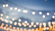 Blurred image of round string lights hanging against a dusky sky, reminiscent of the enchanting evenings at BarnFest.