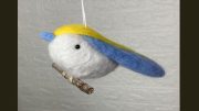 A charming wool felt bird ornament with blue and yellow wings, perfect for adding a touch of whimsy to your 2025 celebrations. This delightful piece hangs gracefully from a string, making it an ideal gift for the boozy bookworms meetup at Steel & Rye on March 27.