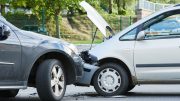 Two cars have collided on a street, the front of one crumpled against the back of the other. Both vehicles are stationary amidst outdoor greenery. As part of Small Business Corner, understanding how businesses should deal with traffic accidents caused by their vehicles is crucial for responsible management.