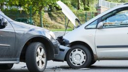 Two cars have collided on a street, the front of one crumpled against the back of the other. Both vehicles are stationary amidst outdoor greenery. As part of Small Business Corner, understanding how businesses should deal with traffic accidents caused by their vehicles is crucial for responsible management.