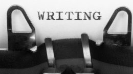 Typewriter hammers striking to imprint the word "WRITING" on a sheet of paper.