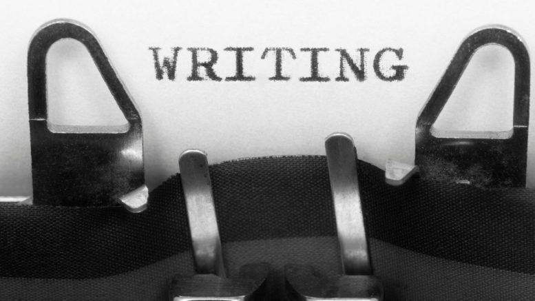 Typewriter hammers striking to imprint the word "WRITING" on a sheet of paper.