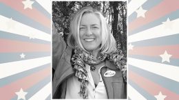Smiling person wearing a scarf and jacket with an "I Voted" sticker, set against a starburst background with stars and stripes.