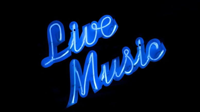 A blue neon sign reads "Live Music" against a black background, setting the mood for the 2025 Milton Summer Concert Series.