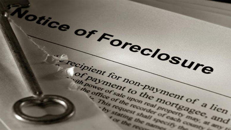 A metal key rests on a torn document titled "Notice of Foreclosure," highlighting legal action in Norfolk County foreclosures and the urgent need for help for homeowners facing non-payment of a mortgage.